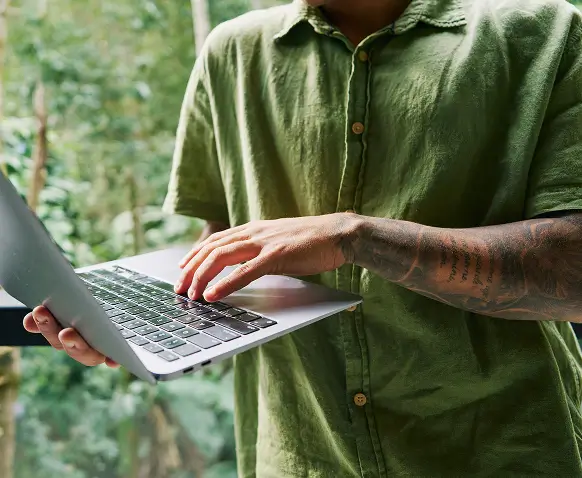 Smiling person working at a laptop with flowers nearby