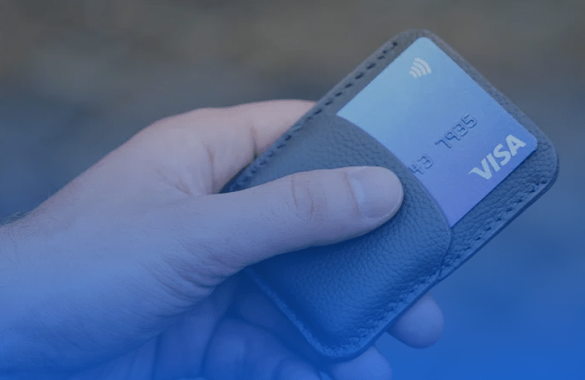 hand holding a wallet with a VISA credit card inside